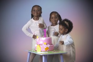 Birthday photograph of siblings celebrating with their sister the celebrant at their home. by C&G Photographers