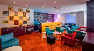 Modern hotel lounge bar interior with colorful seating, wall art, and illuminated bar counter, architectural photography in Nigeria