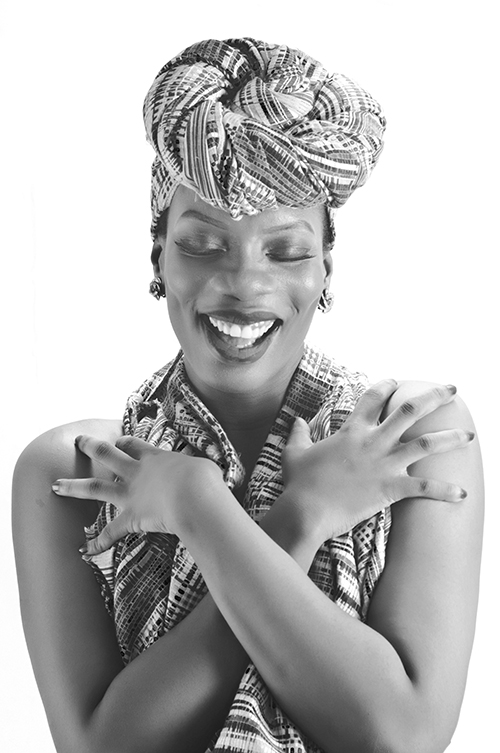 Black and white portrait of a smiling Nigerian woman in traditional headwrap photographed in Lagos