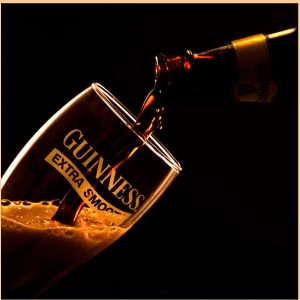 Guinness beer pouring into a glass with foam dark background beverage product photography Lagos Nigeria