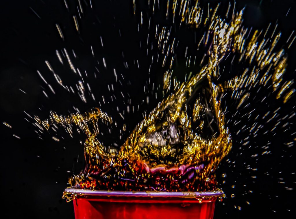 High-speed splash photography of a beverage creating dynamic liquid motion against black background