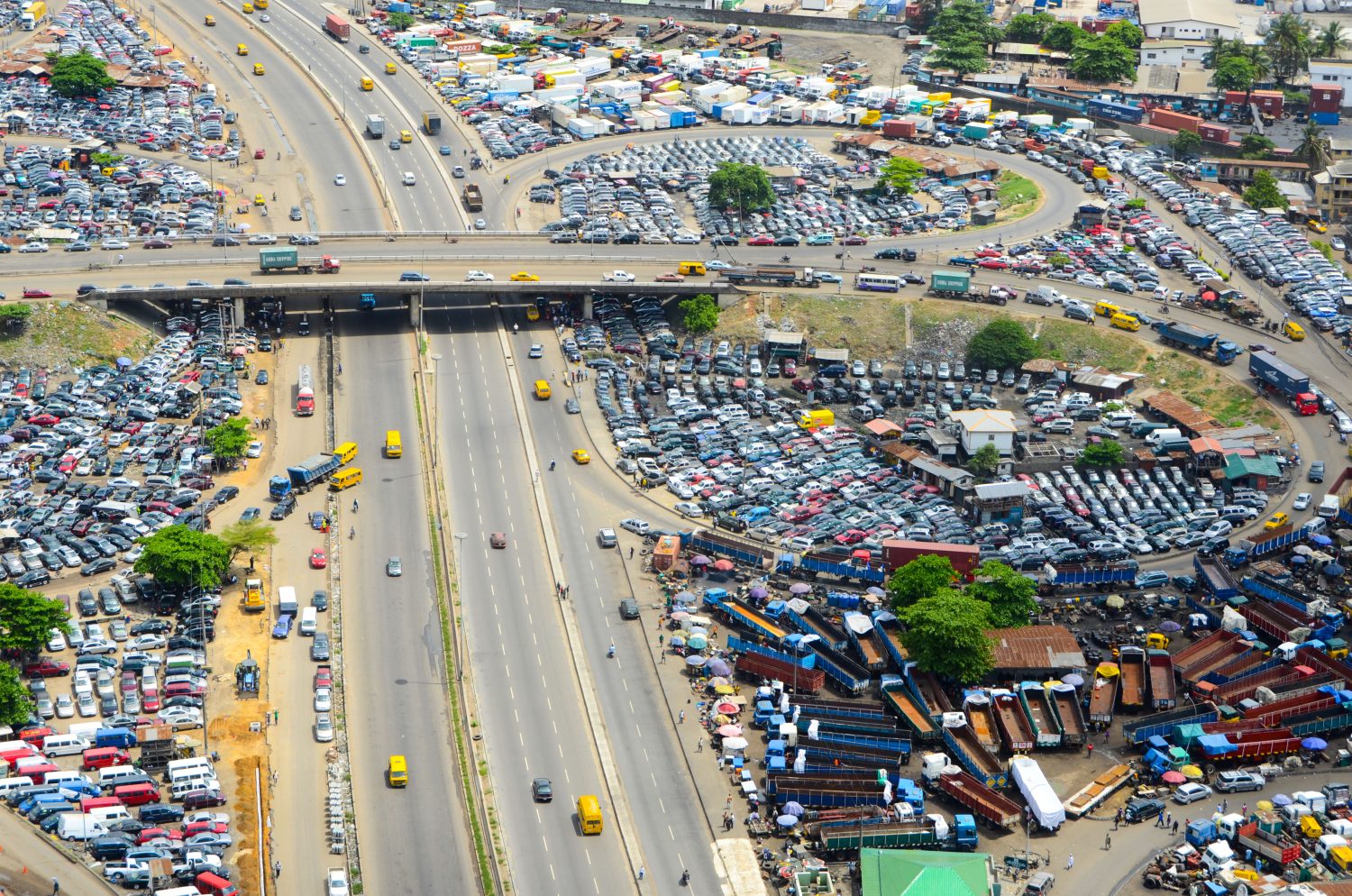 Drone aerial view of Lagos highway with traffic, car markets and dense urban infrastructure