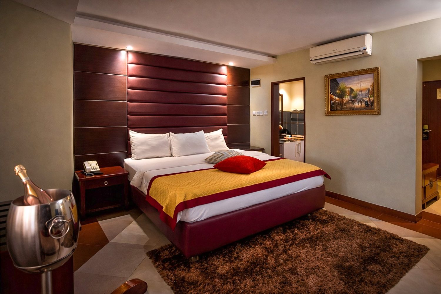 Elegant hotel bedroom featuring a king-size bed, upholstered headboard, and warm ambient lighting for a comfortable guest experience.