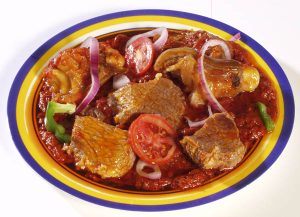 Plate of Nigerian traditional soup with assorted meat, onions, and peppers in a vibrant presentation