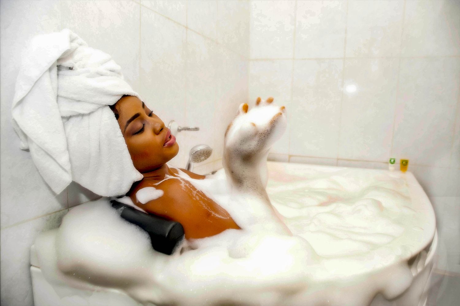 Woman relaxing in a bubble bath in a spa-inspired setting.