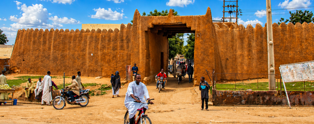 The Great Old Kano Wall in Kano Nigeria with people and motorcycles passing through the historic gateway