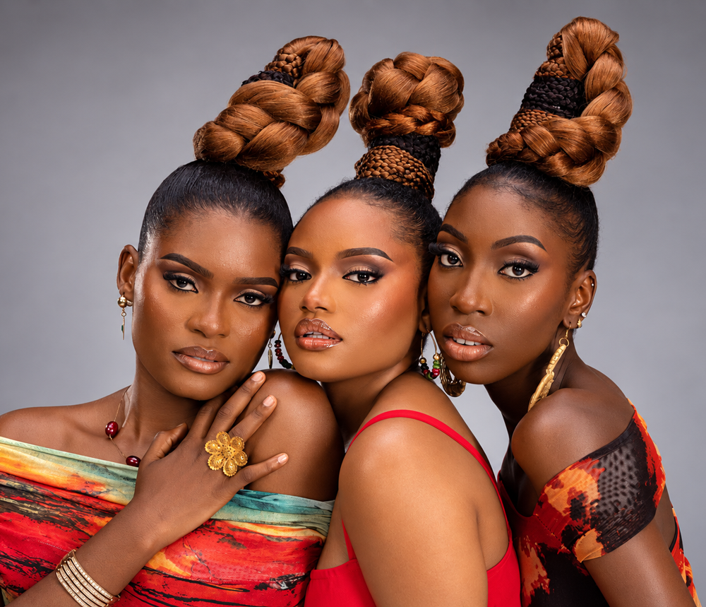 Three women showcasing braided updo hairstyles, makeup and fashion in a studio beauty portrait.